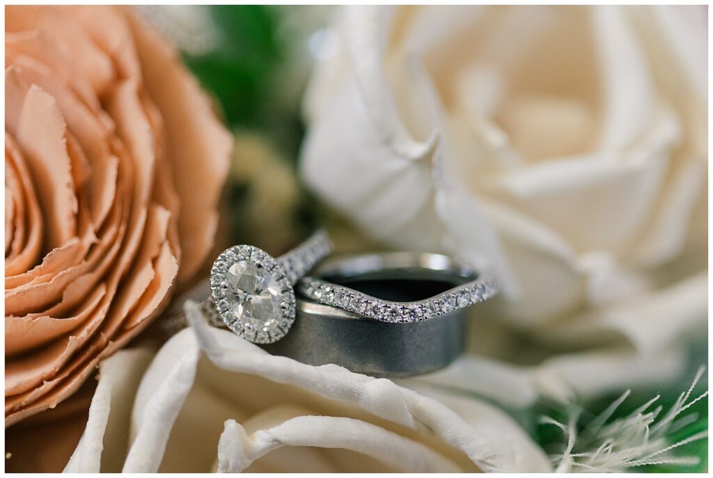 Close-up of the bride and groom’s wedding rings nestled among cream and peach-colored roses.