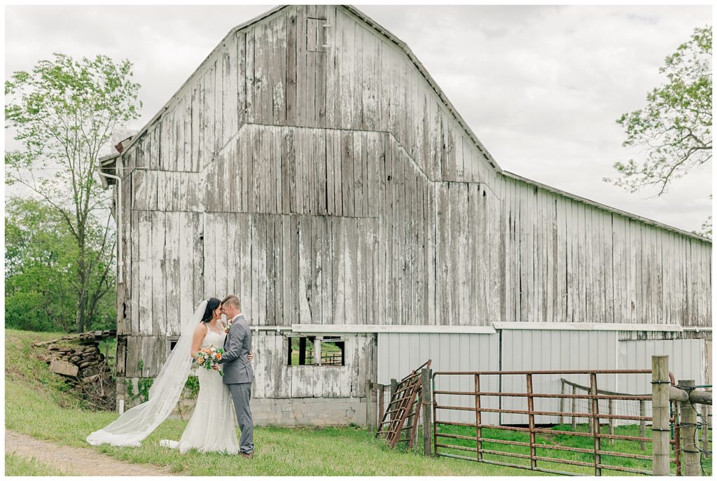 Bride and groom dancing in front of a rustic barn, sharing a joyful moment on their wedding day.