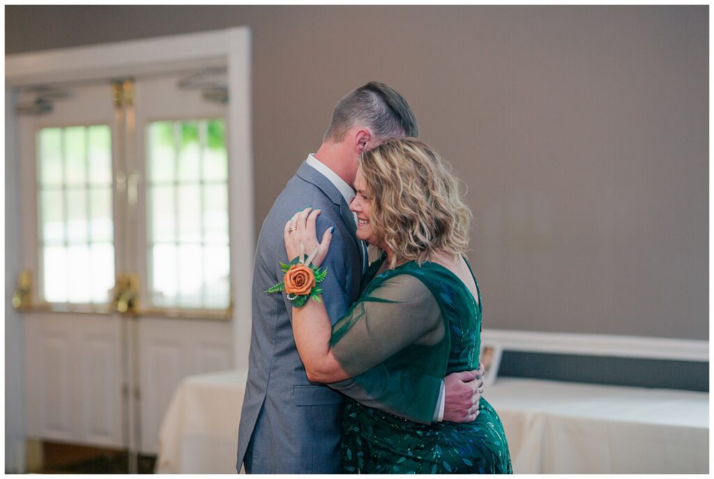 Groom dancing with his mother during the reception, both smiling and sharing an emotional moment.