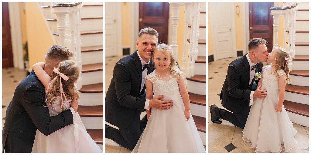 Groom kneels beside a young flower girl in a white dress as they smile together on the wedding day.