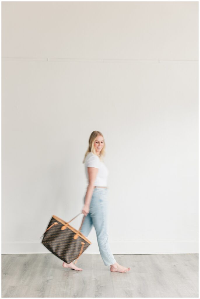Female entrepreneur walking with a wicker bag, looking over her shoulder in a light-filled space.