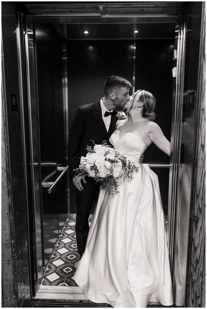 Black and white photo of the couple sharing a romantic moment in the vintage elevator, bride holding her bouquet close.
