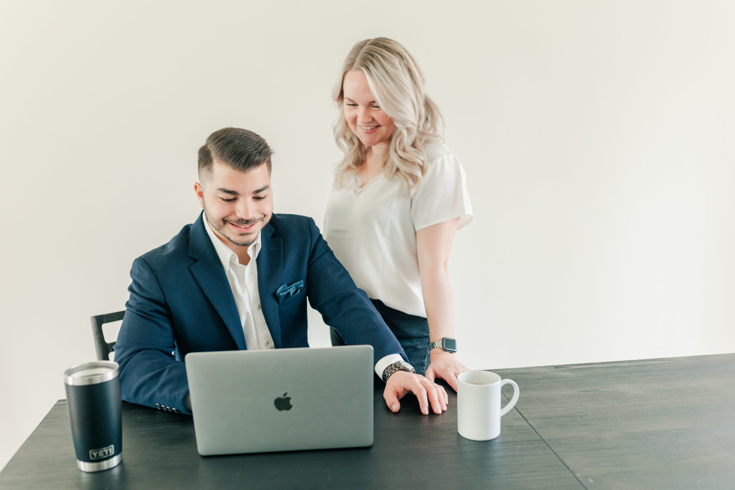 Man and woman collaborating at a desk with a laptop and coffee mug during a brand session