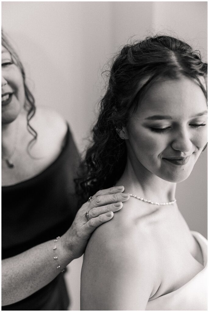 Close-up of bride smiling as her mom places a hand on her shoulder before wedding ceremony