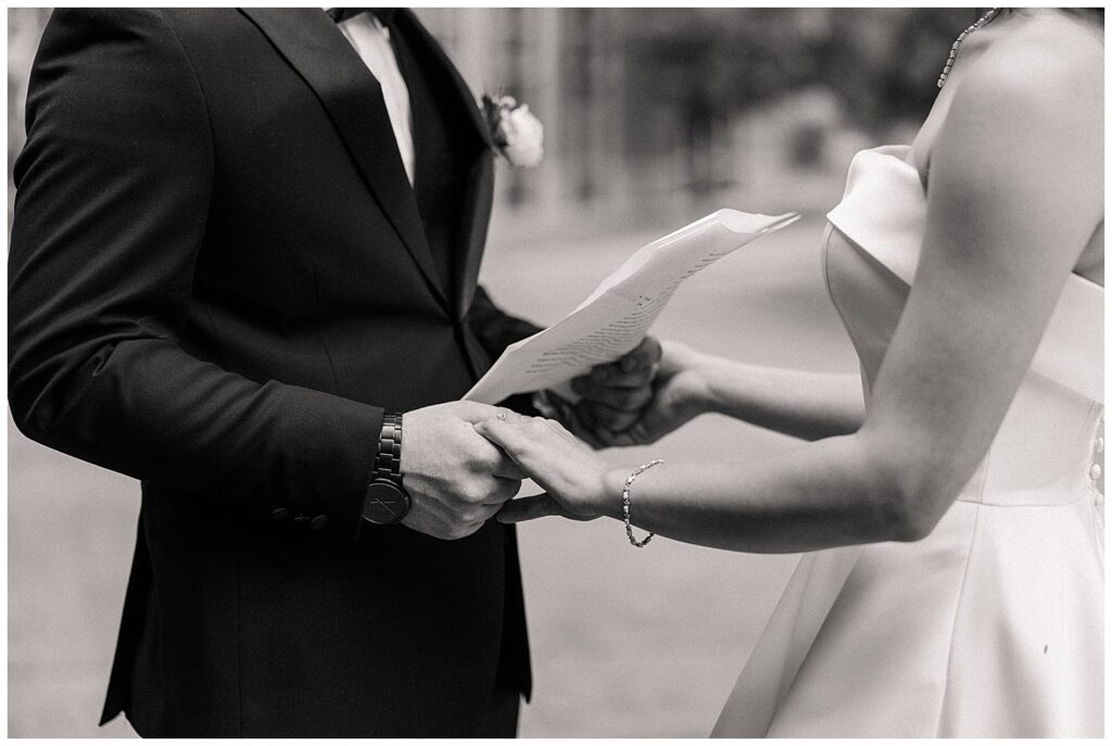 Close-up of hands exchanging handwritten vows during private ceremony moment
