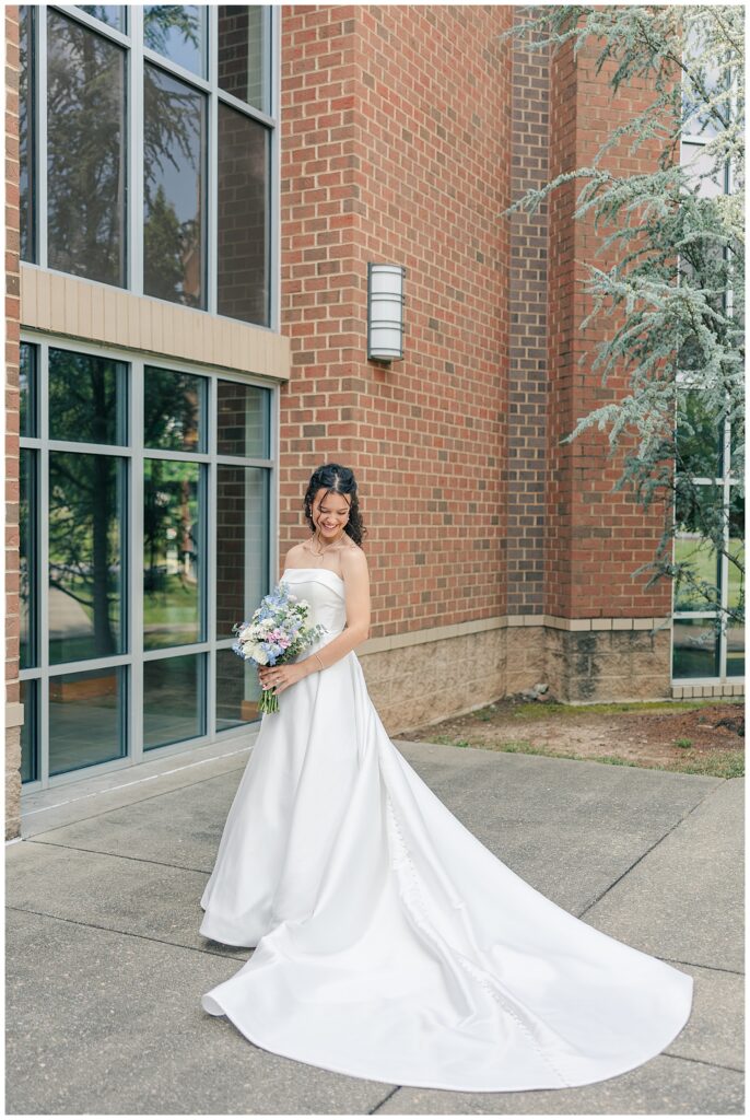 Bride standing in front of large windows in strapless gown holding pastel bouquet — Zoe Evans Photography