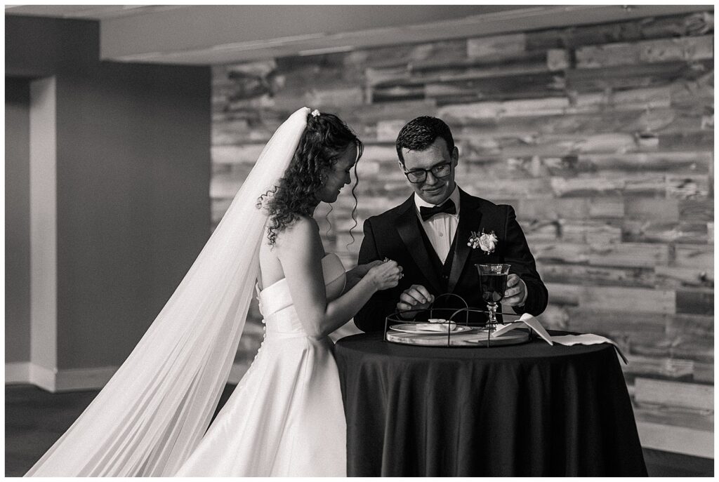 Black and white candid of bride and groom sharing a moment at sweetheart table