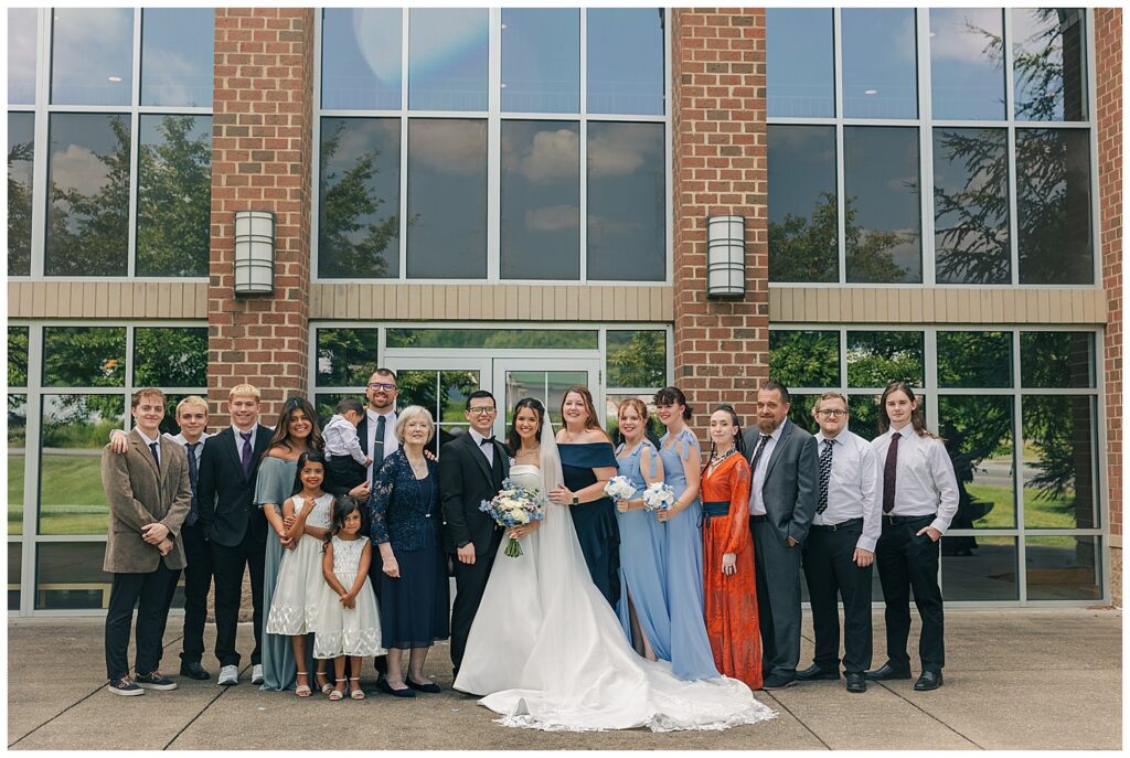 Extended family group photo with bride and groom in front of brick wedding venue