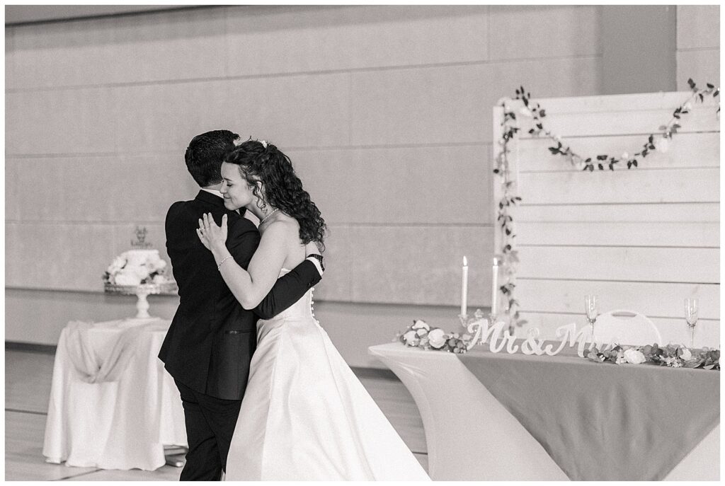 Black and white image of bride and groom embracing on the dance floor during reception