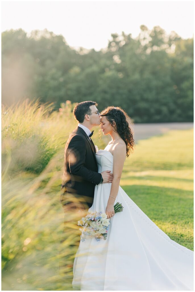 Bride and groom embracing in a golden field at sunset