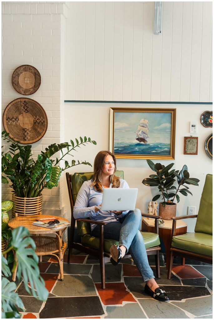 Cozy travel advisor brand photo of Lauren working on her laptop in a boutique hotel lounge, captured during her New England branding session by Zoe Evans.