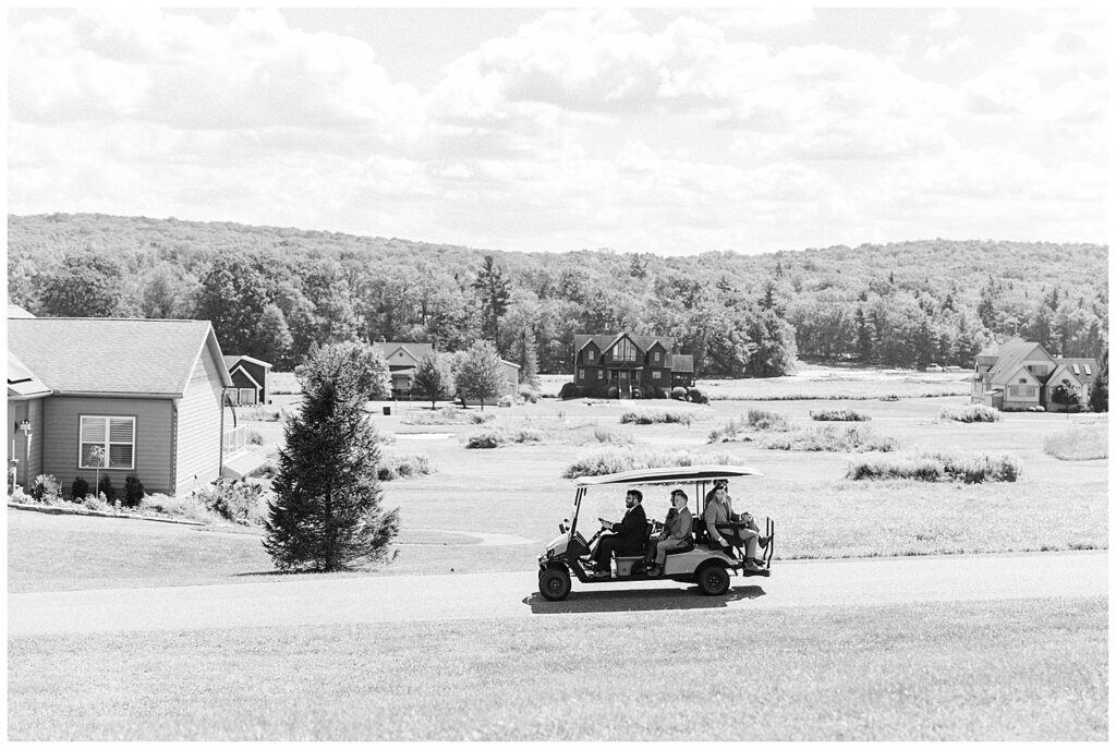 Black and white photo of wedding guests arriving by golf cart to Red Barn Inn in Deep Creek | documentary-style wedding moment by Zoe Evans Photography