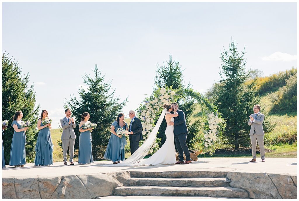 Outdoor wedding ceremony with full bridal party in front of a circular floral arch at Red Barn Inn in Deep Creek, Maryland