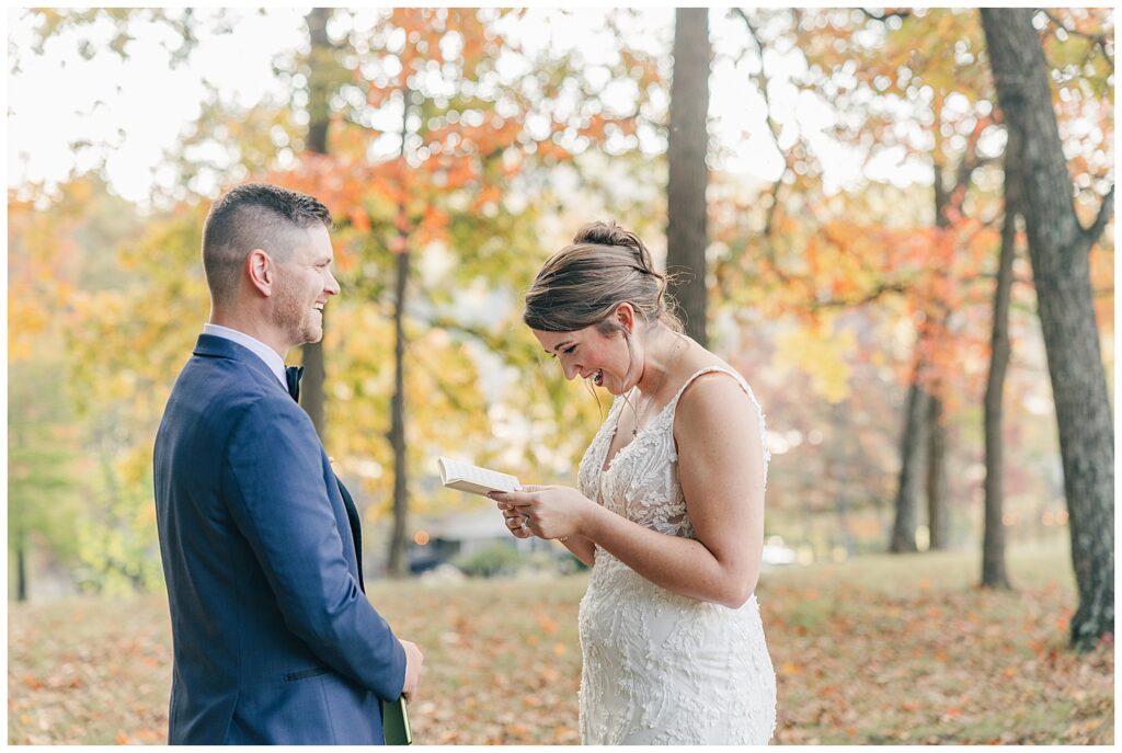 Bride reading private vows to groom during their first look among colorful autumn trees at Athena Estate.