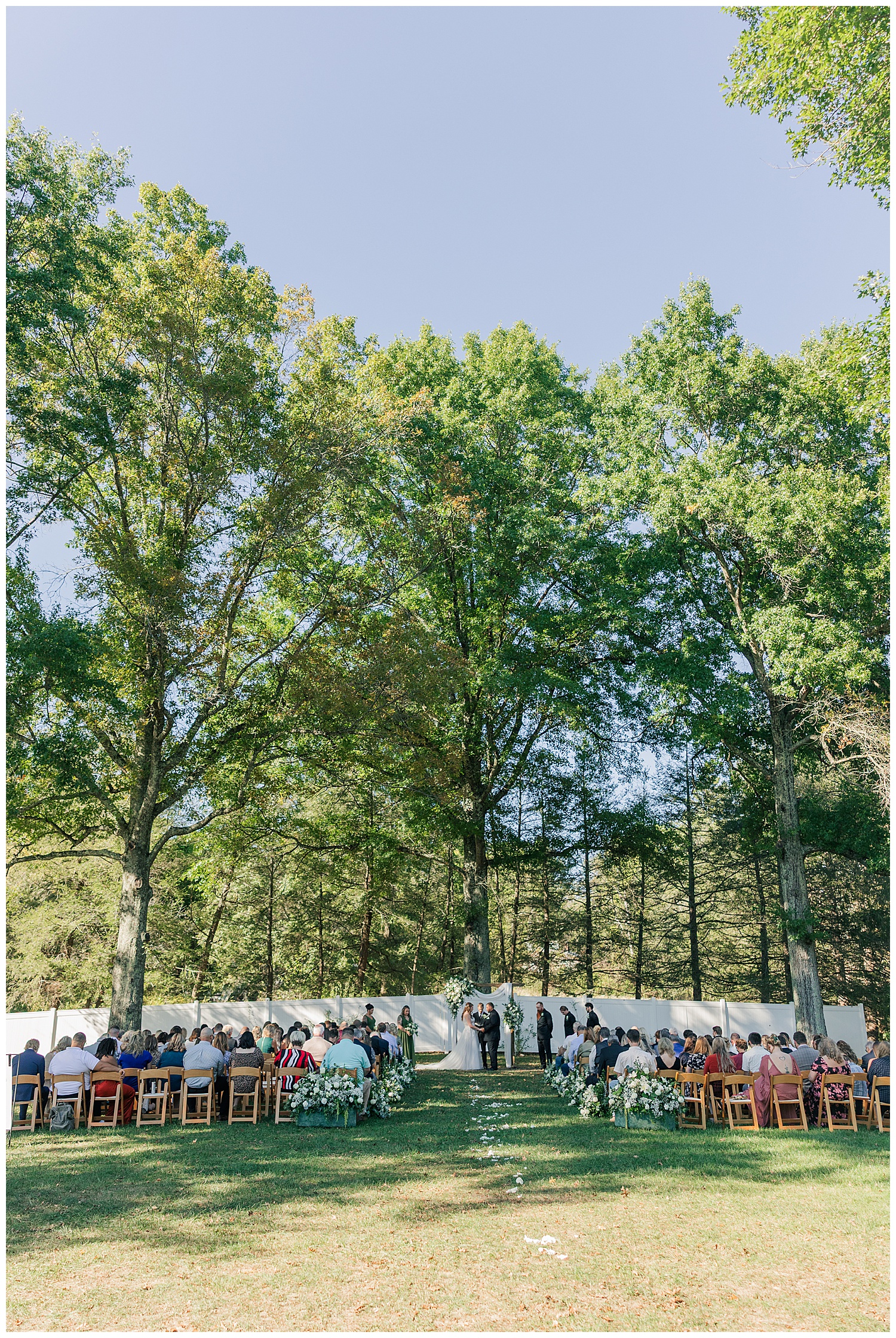 Scenic outdoor ceremony under tall trees at Ellis House in Fairmont West Virginia, photographed by Zoe Evans Photography.