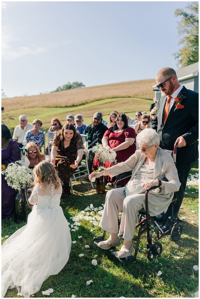 Flower girl walks down the aisle with her great-grandmother and flower girl at Palomino Pastures in Ritchie County, WV during a heartfelt fall wedding ceremony.