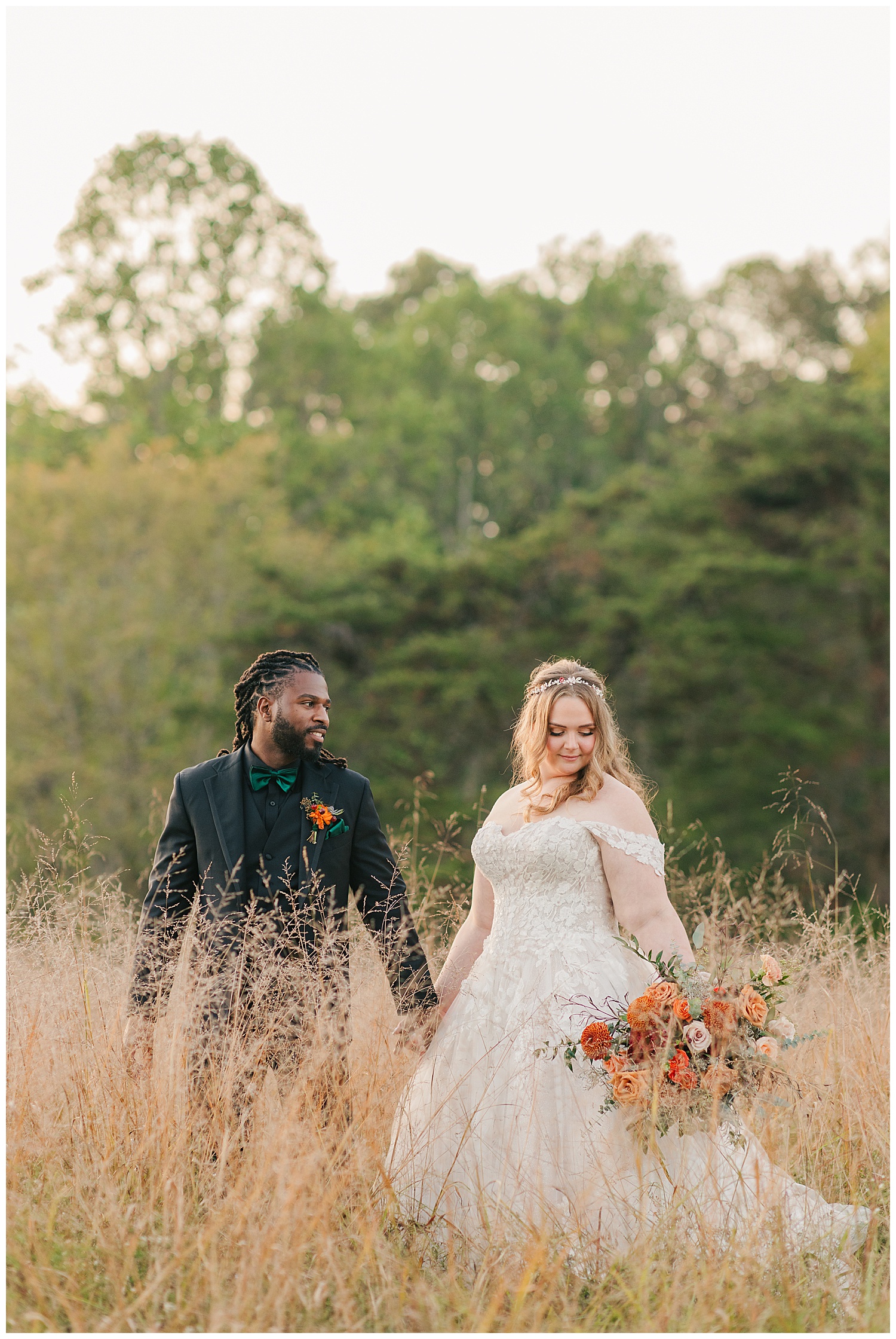 Bride holding terracotta and blush floral bouquet while standing with groom in a lush field at Palomino Pastures wedding