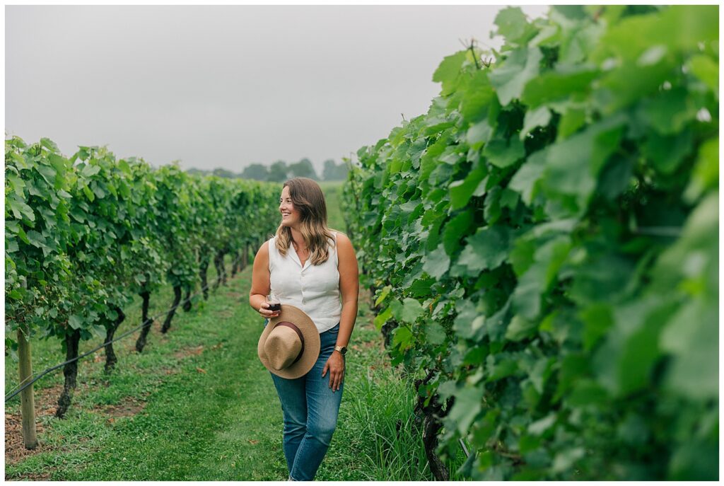 Brand photo of a woman holding a straw hat and walking through a vineyard, highlighting slow travel and outdoor exploration.