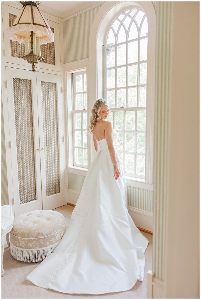 Elegant bridal portrait in a sun-filled window room at Great Marsh Estate, showcasing the full wedding gown.