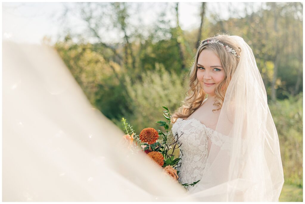 Bride smiling softly under her veil with a fall-inspired bouquet by The Flower Daddy at Palomino Pastures wedding venue.