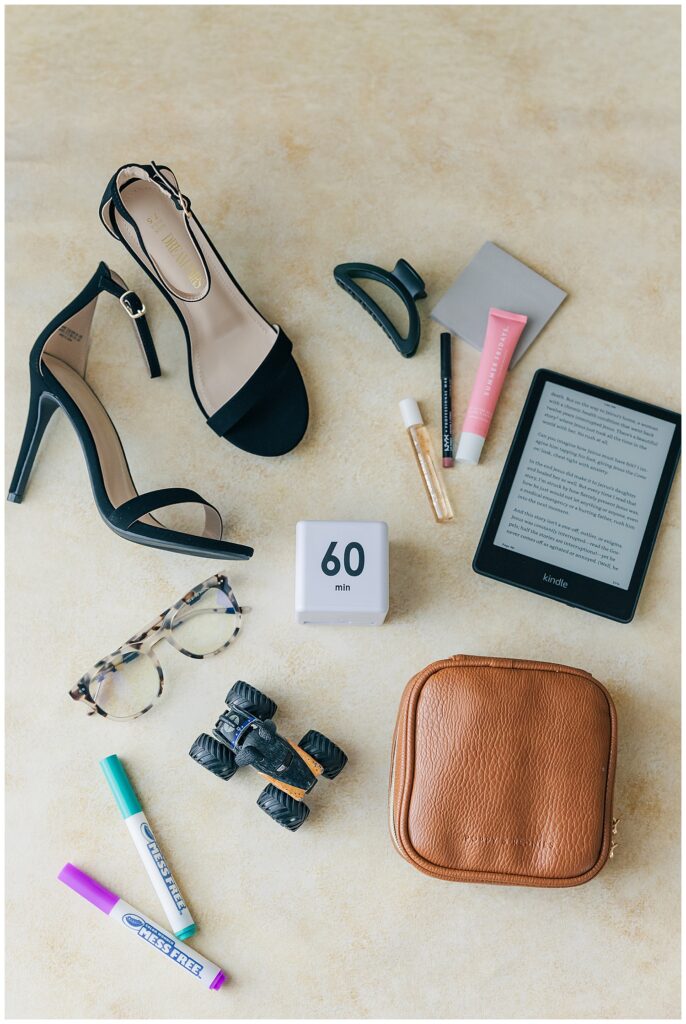 Flat lay of personal and professional essentials: heels, tech, makeup, keys, and notebooks—showcasing the balance of life and business.