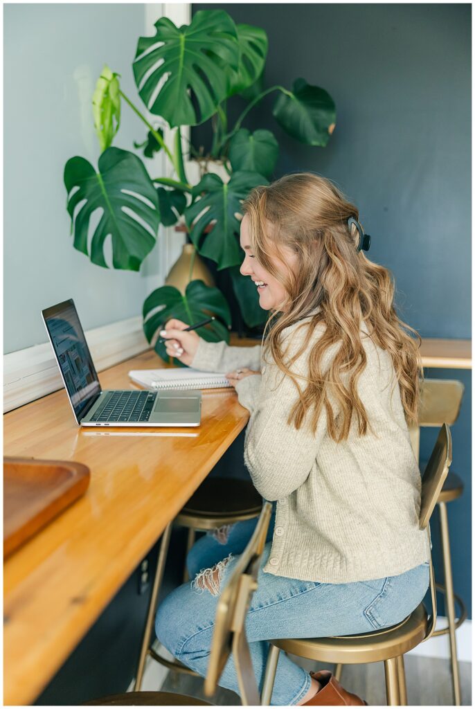 Over-the-shoulder shot of Liz working on her laptop, highlighting a relaxed brand session scene with cozy style and productivity.