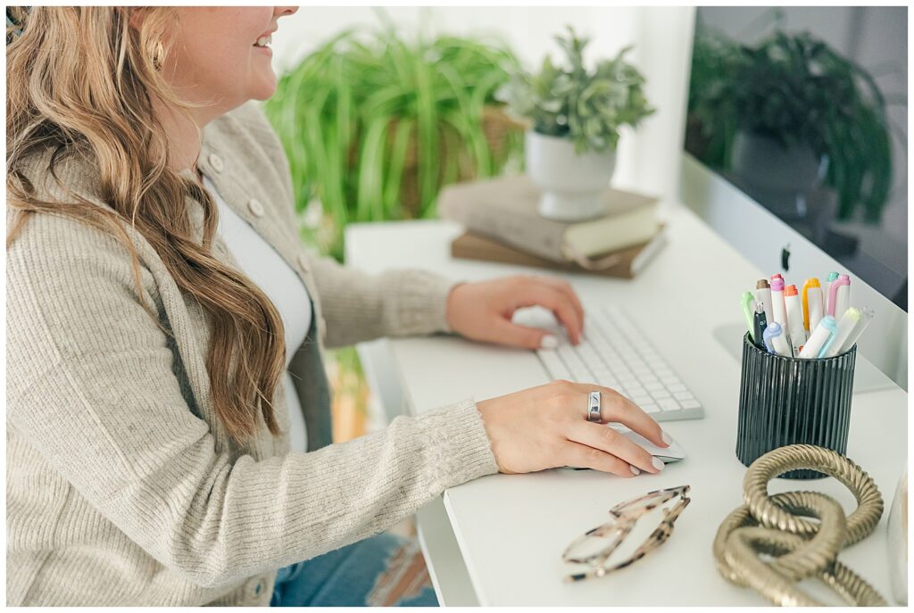Close-up of Liz’s hands writing in a notebook with a planner, glasses, and a latte nearby—capturing behind-the-scenes strategy as a virtual assistant.