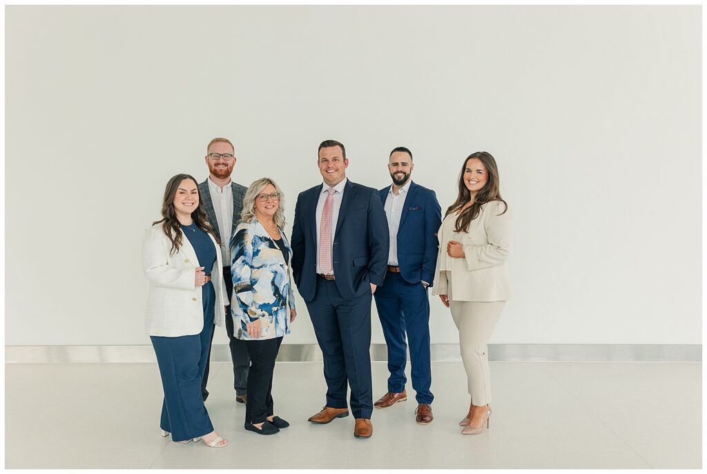 Professional brand photography of a six-person business team in coordinated outfits, captured in a minimalist white studio to emphasize unity, clarity, and professionalism.