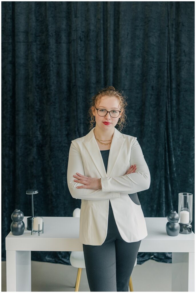 Confident female entrepreneur in a white blazer with arms crossed at The Onyx Room West Virginia for Brittany Ann’s Events branding session in Morgantown WV